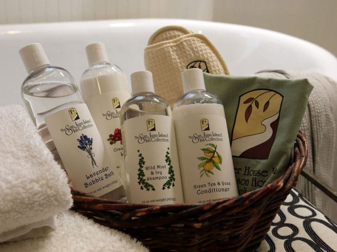 Basket of bath products near towels and a tub