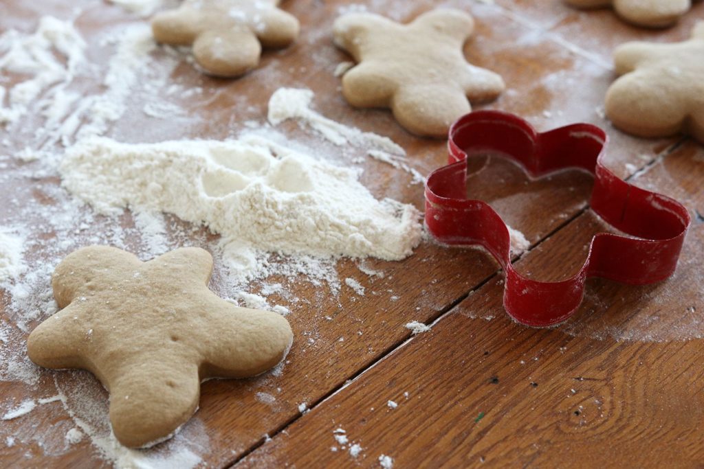 Baked Gingerbread Persons ready for decoration on floured wooden table