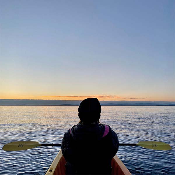 Woman paddling a kayak at sunset