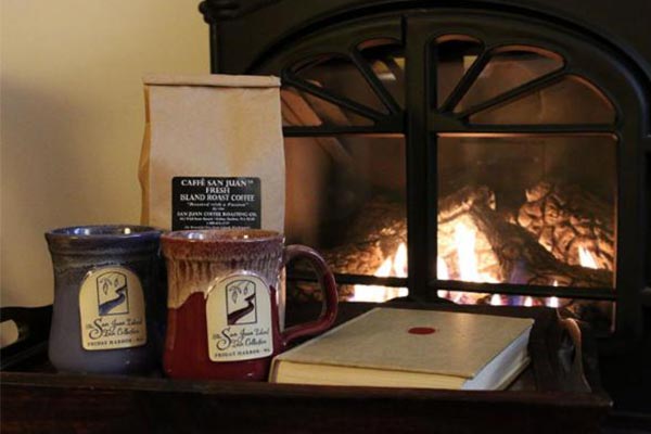 Two mugs and a book on a tray in front of a fireplace