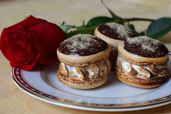 Three macarons on a plate with a rose