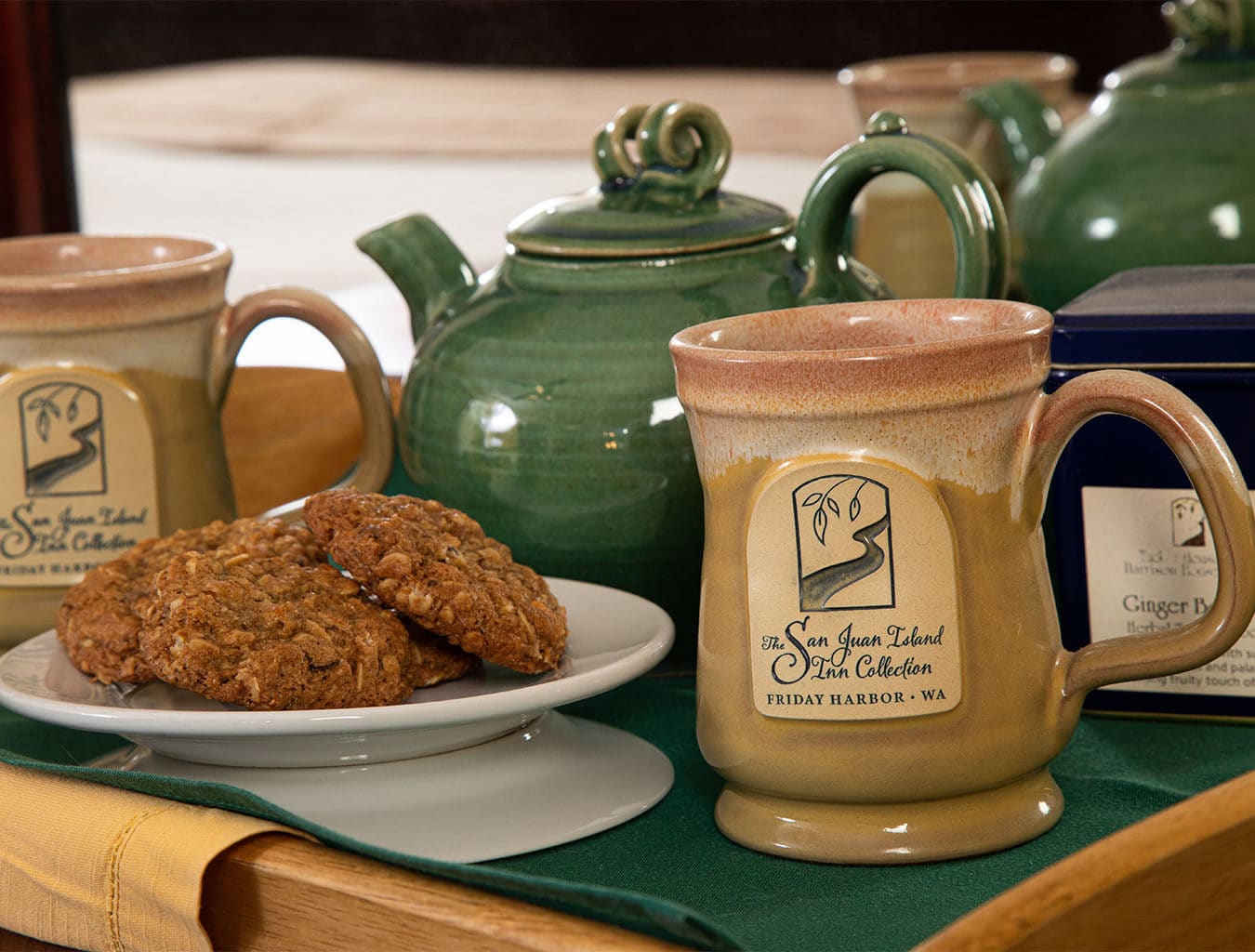 yellow mug, tea pot, and oatmeal cookies on a plate