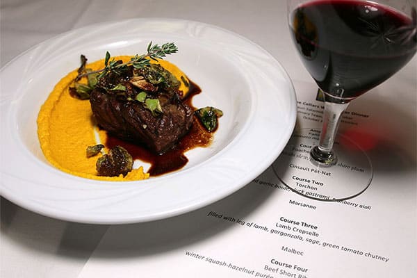 beef entree and glass of wine on top of a printed menu